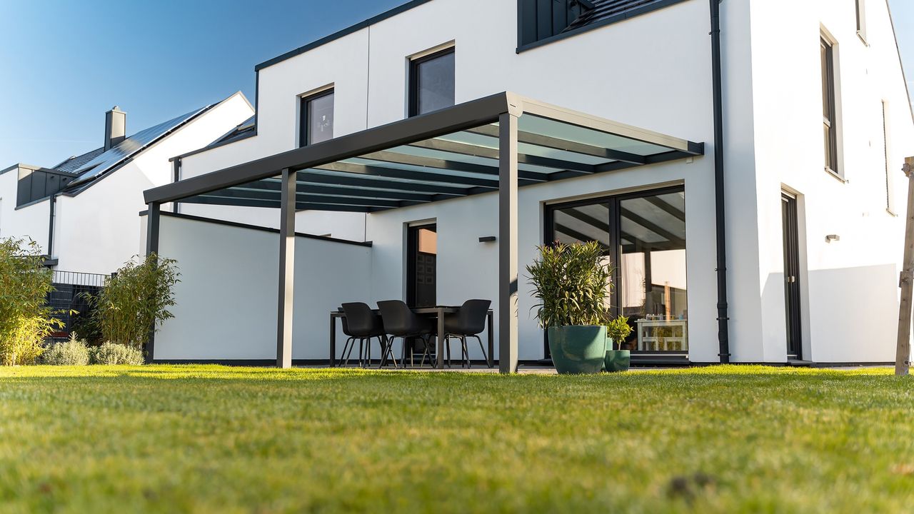 Terrassenüberdachung aus Aluminium in Anthrazit mit Glasdach an einem weißen Einfamilienhaus