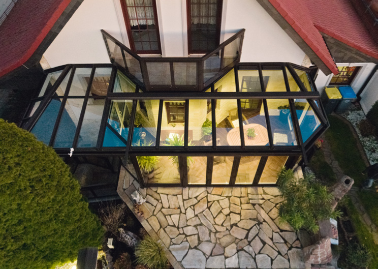 Eleganter Wintergarten mit einem Pultdach und seitlichen Abwalmungen, die für harmonische Übergänge und eine abwechslungsreiche Optik sorgen.