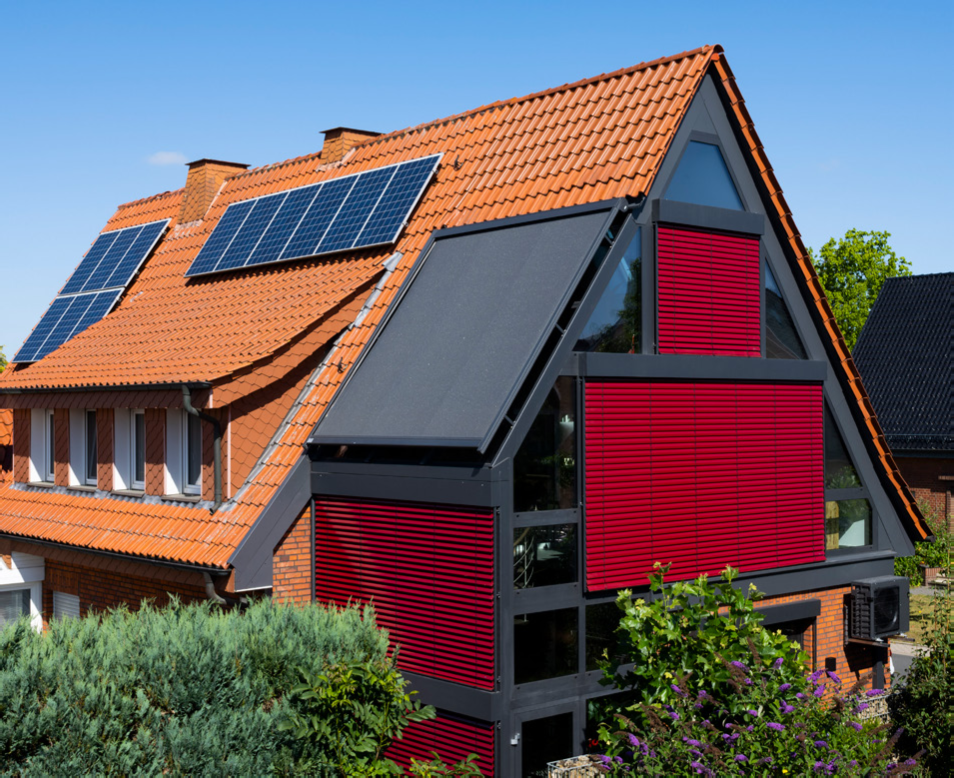 Individuelle Gestaltung durch Farbenvielfalt: Ein mehrgeschossiger Wintergarten mit pulverbeschichteten Profilen in Anthrazit und markanten roten Farbakzenten durch die Beschattung.